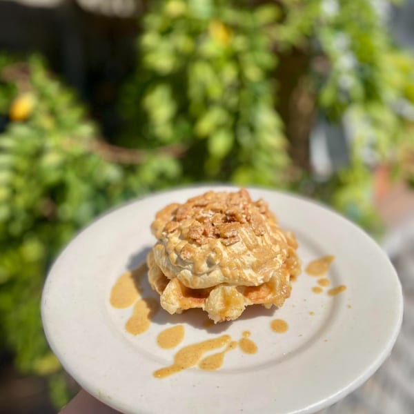 Water Street Waffle Co's waffle topped with whipped cream, caramel drizzle, and crunchy cereal.