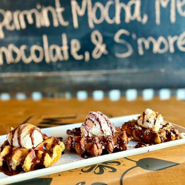 Three Water Street Waffle Co. waffles with ice cream, chocolate drizzle, and various toppings.