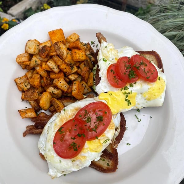 Water Street Waffle Co. breakfast plate with home fries and two pieces of toast topped with eggs and tomatoes.